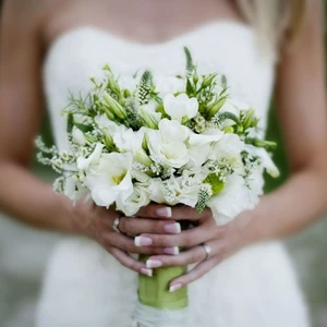 Image of a close up of  a bridal bouquet in the hands of a bride in a white dress