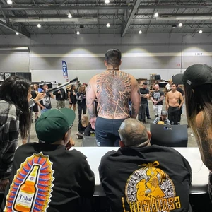 A photo from the portland tattoo expo with two judges looking at a large tattoo on a persons back during a judging.