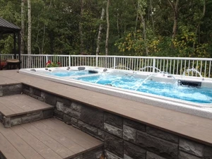 Outdoor swim spa with jets surrounded by a custom deck. 