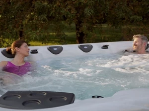 Two adults enjoy a bubbling hot tub outdoors.