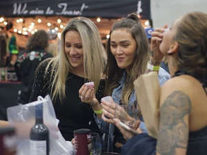 Three girls at a booth at the seafood & wine festival trying wine