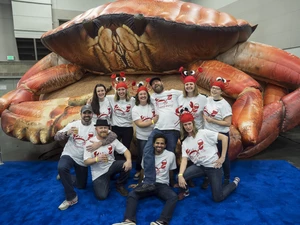 A group of people in matching t-shirts standing in front of a large inflatable crab at seafood & wine fest