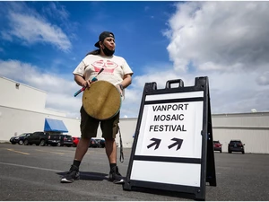 Image of man with drum and Vanport Mosaic Festival "this way" sign