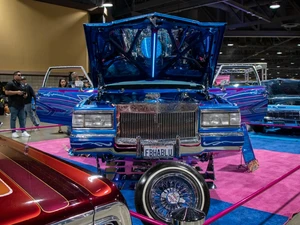 A photo from the Lowrider Experience showing a blue car with the doors and hood open