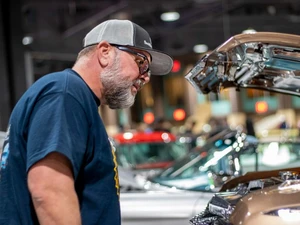 A photo from the Lowrider Experience showing a man looking into the hood of a car