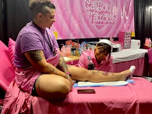 A person getting tattooed on their shin at the tattoo expo
