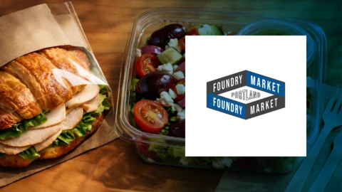 A detailed image of a turkey croissant sandwich and Greek salad next to a logo for Foundry Market.