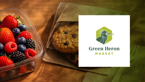 A detailed image of fresh berries in a container and cookies next to a logo for Green Heron Market.
